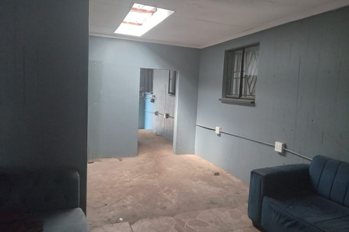 An interior living space featuring a skylight, exposed electrical conduit, and tiled flooring, currently requiring significant cosmetic updates and finishing work.