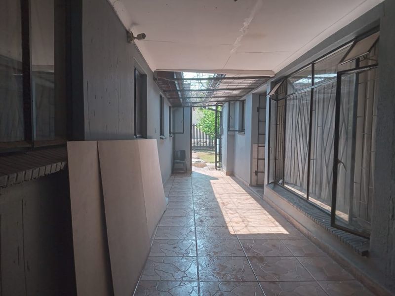 A covered outdoor patio area featuring tiled flooring, metal security fixtures, and direct access to the rear garden.