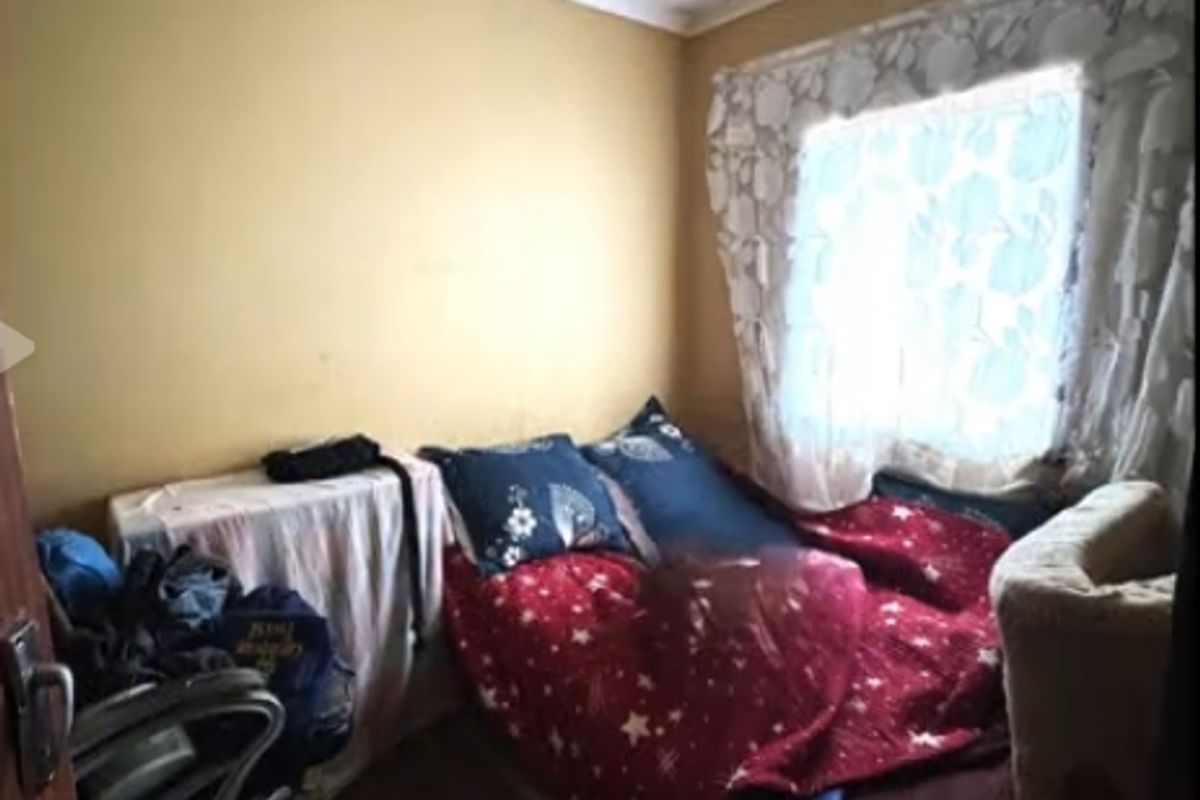 A compact bedroom featuring a window with natural light, requiring cosmetic updates to the walls and ceiling to improve its overall condition.