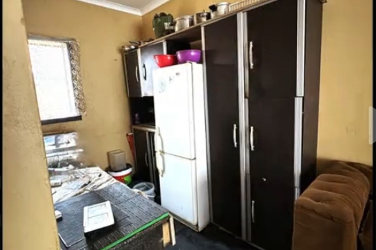 A compact kitchen area featuring built-in cabinetry and basic lighting, currently requiring significant cosmetic updates and maintenance to improve its overall condition.