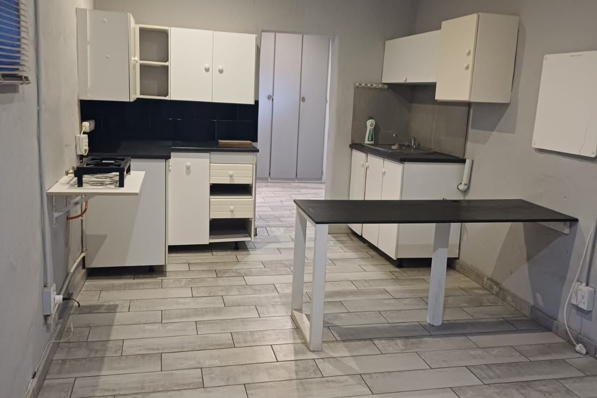 A functional kitchen space featuring white cabinetry, dark countertops, and modern grey tiled flooring, offering a clean canvas for potential updates.