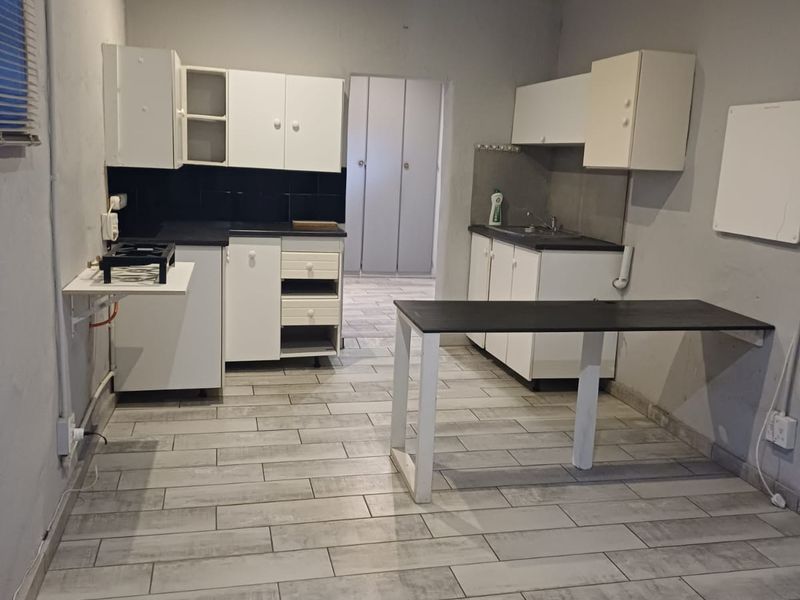 A functional kitchen space featuring white cabinetry, dark countertops, and modern grey tiled flooring, offering a clean canvas for potential updates.