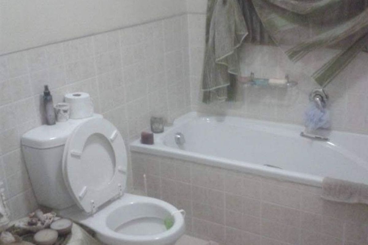 A functional bathroom featuring a standard bathtub, toilet, and tiled wall finishes, offering a basic layout suitable for modernization.