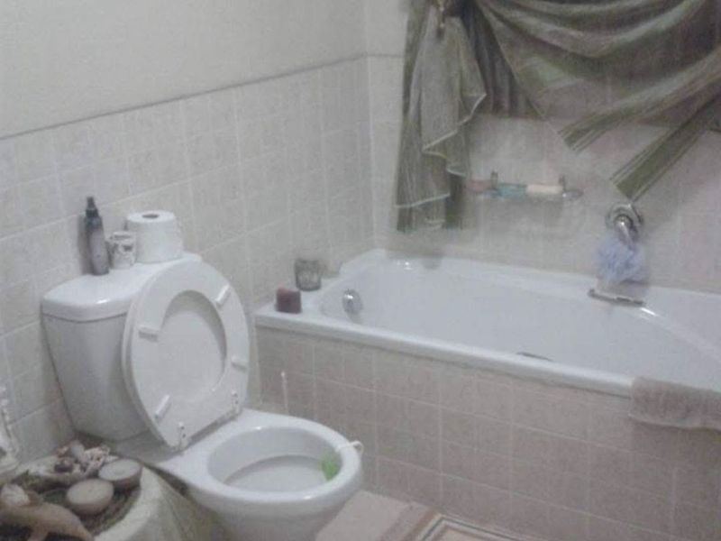 A functional bathroom featuring a standard bathtub, toilet, and tiled wall finishes, offering a basic layout suitable for modernization.