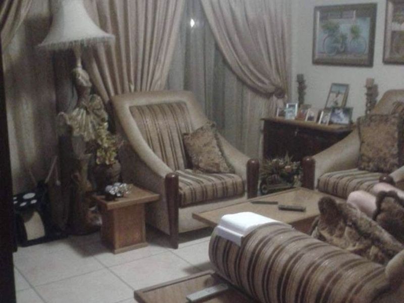 A living room area featuring tiled flooring and window treatments.