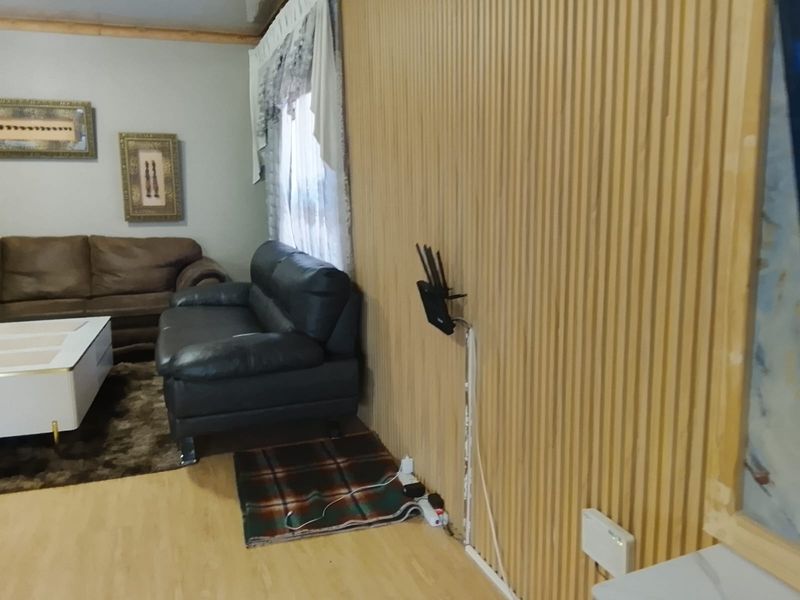 Living room featuring timber slat wall paneling and laminate flooring, currently showing exposed wiring and unfinished trim details.
