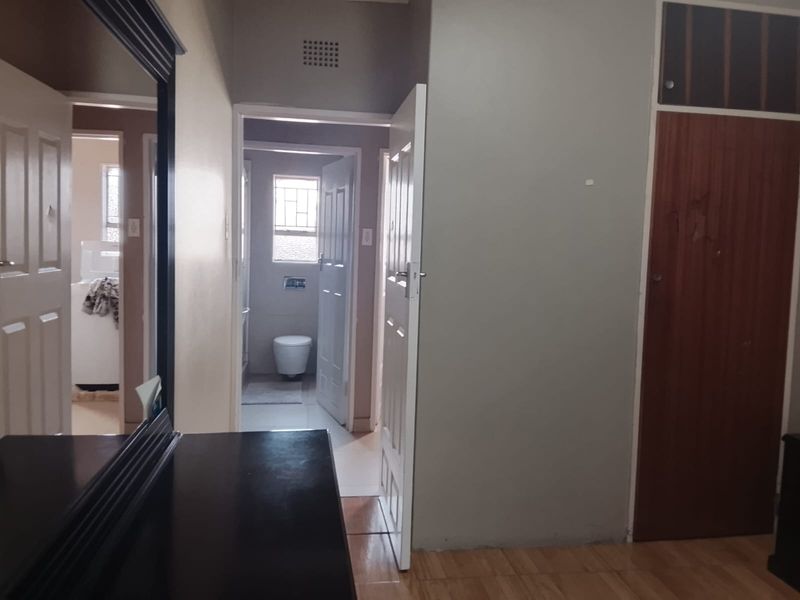 A functional hallway featuring tiled flooring, built-in storage cupboards, and access to adjacent rooms including a bathroom.