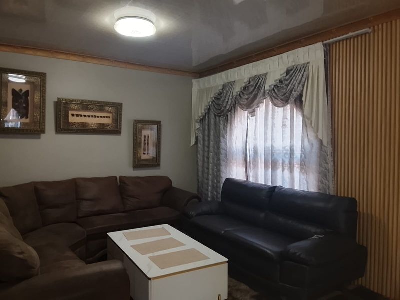 A living room featuring a glossy ceiling finish, crown molding, and vertical wall paneling, providing a traditional base for interior updates.