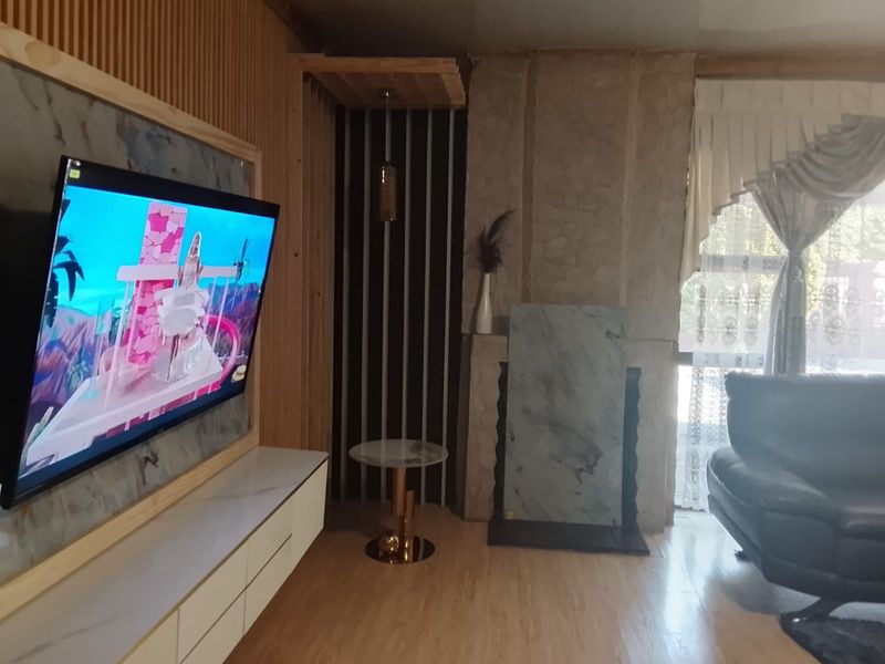Living room featuring a stone accent wall, timber slat paneling, and a built-in media console with marble-look finish.