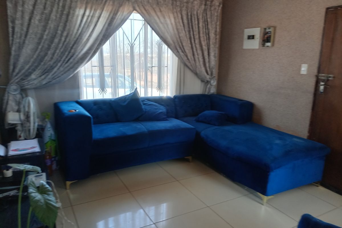 A living room featuring tiled flooring, a window with security bars, and cove cornicing, providing a functional space with potential for cosmetic updates.