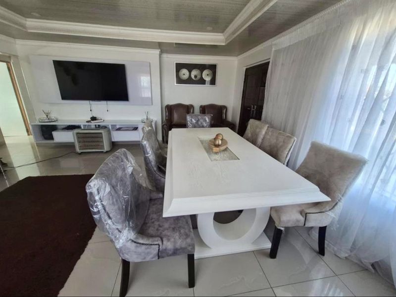 Spacious living and dining area featuring polished tiled flooring, a recessed ceiling design, and a modern built-in media console.