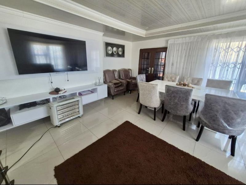 A bright dining room featuring polished tiled flooring, crown molding, and elegant french doors, providing a clean and functional space for family meals.