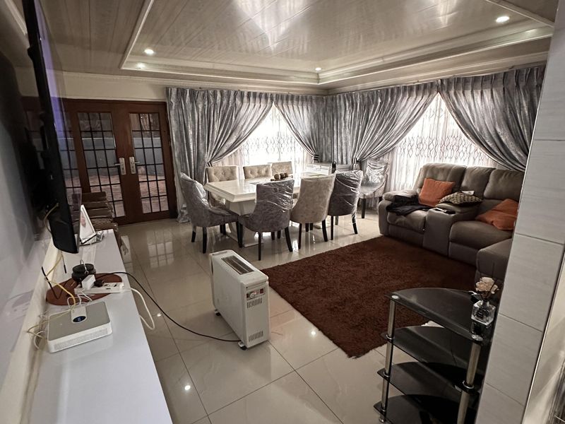 Spacious open-plan living and dining area featuring tiled flooring, recessed ceiling details, and direct access to the exterior through glass-paneled french doors.