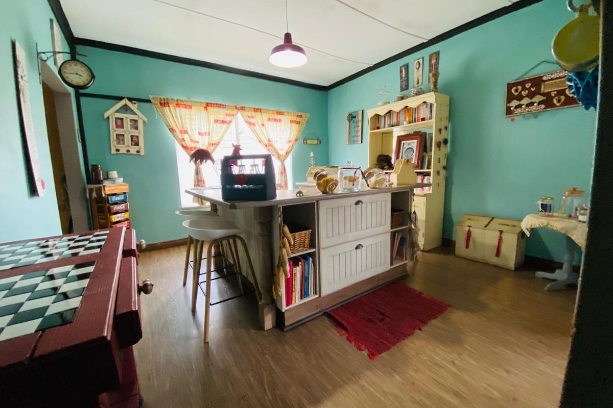 A kitchen area featuring a central island with built-in shelving and laminate flooring, offering a functional space with potential for modern updates.