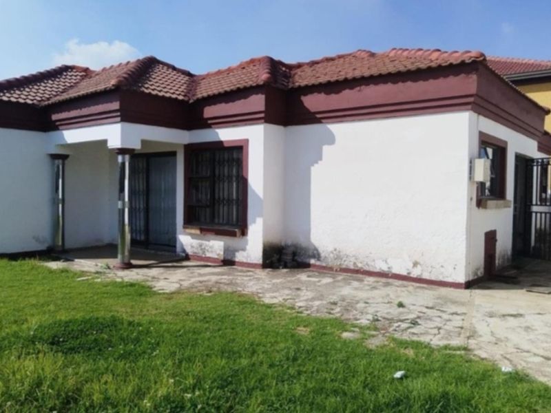 Front exterior view of a single-story house featuring a tiled roof, concrete columns, and security bars, showing signs of exterior wall wear.