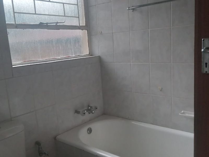 A functional bathroom featuring a bathtub, toilet, and tiled walls, offering a blank canvas for modern renovation and updates.