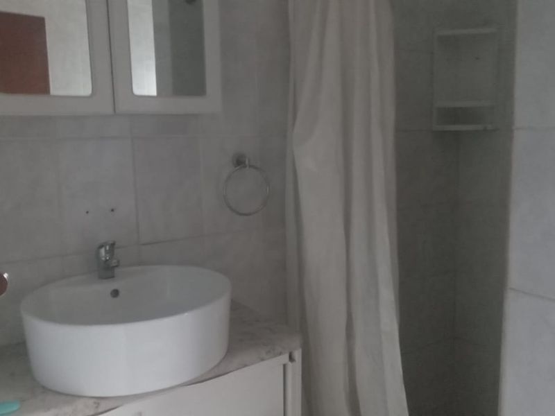 A functional bathroom featuring a vessel sink vanity, wall-mounted medicine cabinet, and a shower enclosure with tiled walls.