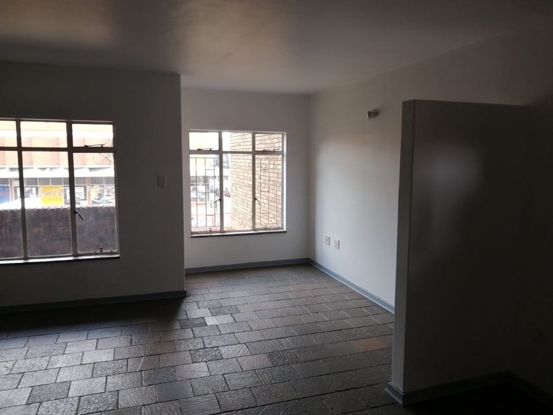 An empty living area featuring stone tile flooring and large metal-framed windows, providing a neutral canvas for interior design.