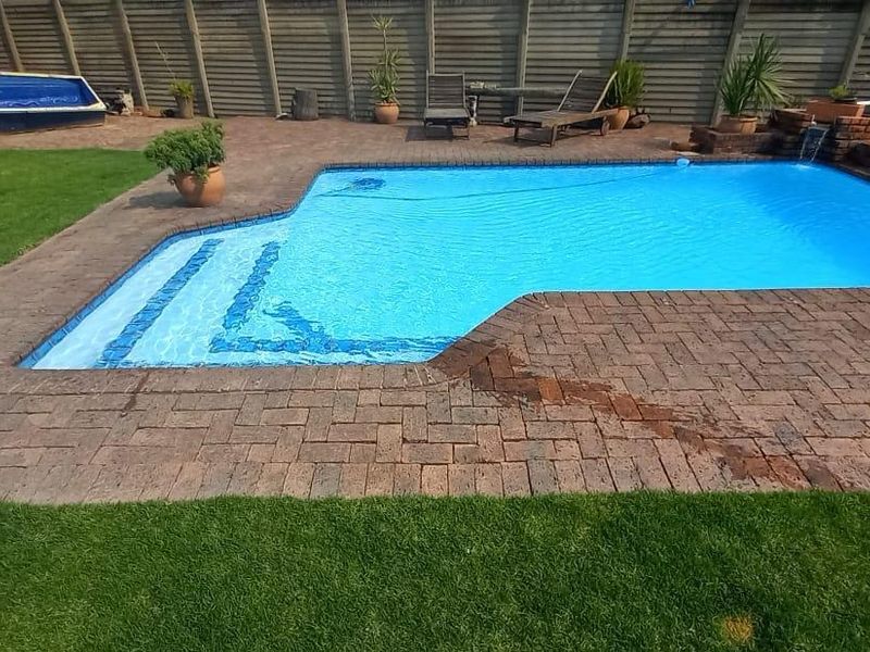 Outdoor pool area featuring a swimming pool with brick paving surround, a small brick water feature, and perimeter timber fencing.
