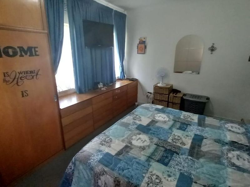 A bedroom featuring built-in wooden cupboards and a window with curtains.