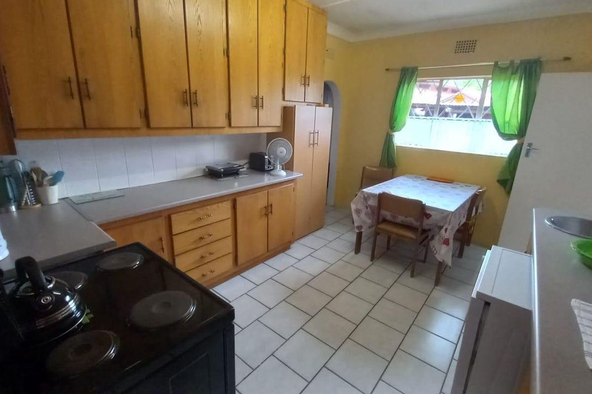 A functional kitchen featuring wooden cabinetry, tiled flooring, and a built-in stove, offering a dated aesthetic with potential for modern renovation.