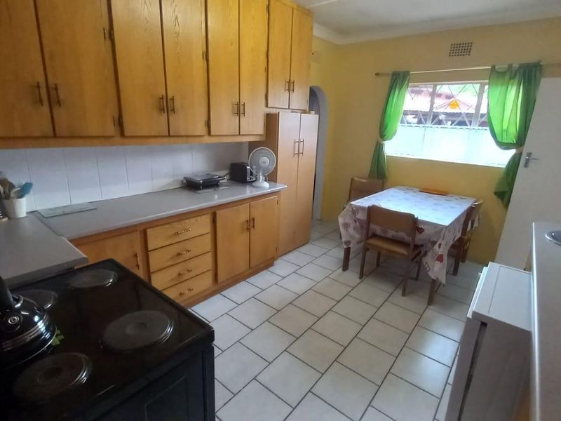 A functional kitchen featuring wooden cabinetry, tiled flooring, and a built-in stove, offering a dated aesthetic with potential for modern renovation.