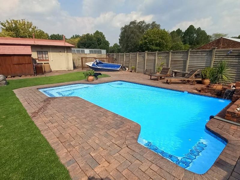 Outdoor pool area featuring a swimming pool with brick paving surround, a brick planter box, and a perimeter precast concrete wall.