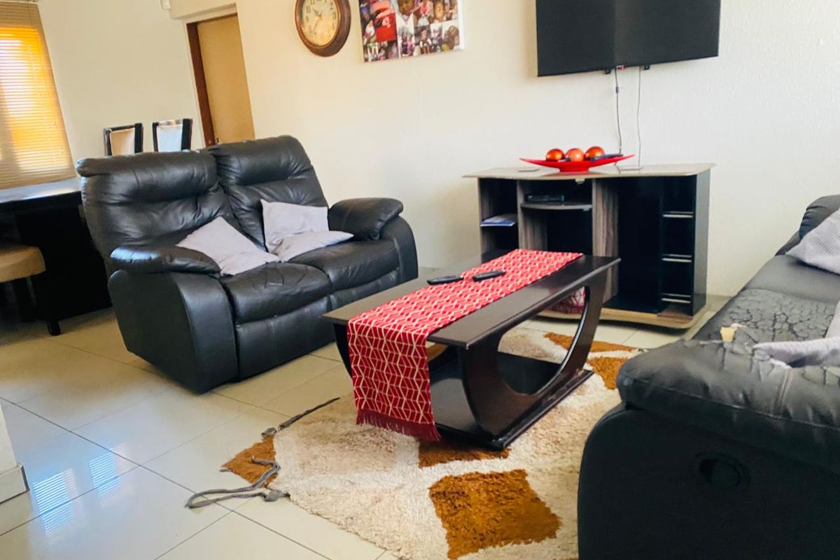 A functional living room area featuring tiled flooring and a wall-mounted television setup.