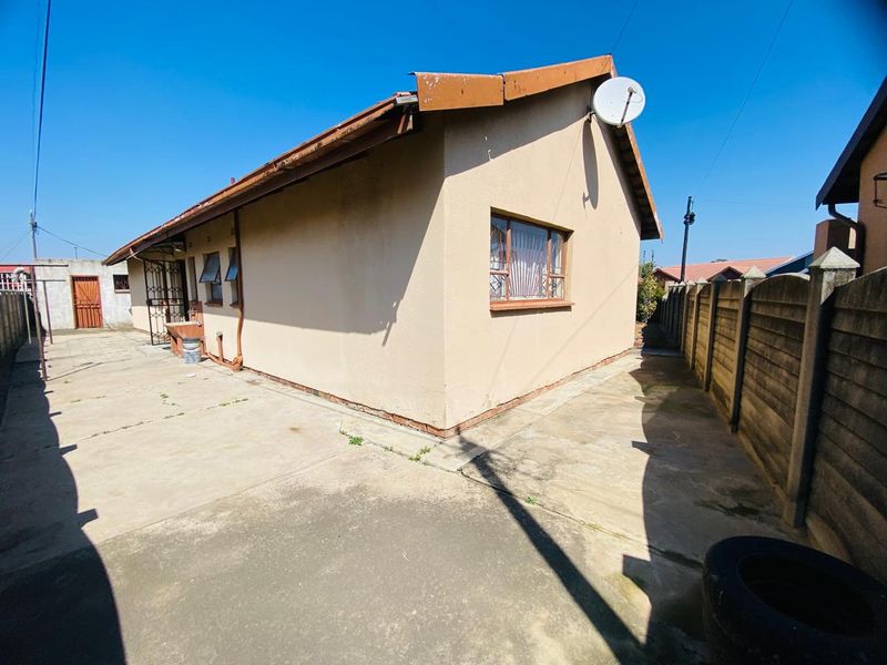 Rear exterior view of the house featuring concrete paving, a precast boundary wall, and an external wash basin area.
