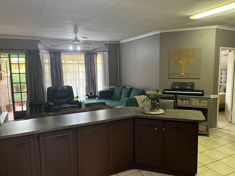 Open plan living area featuring tiled flooring, a kitchen island with dark cabinetry, and direct access to the patio through sliding glass doors.