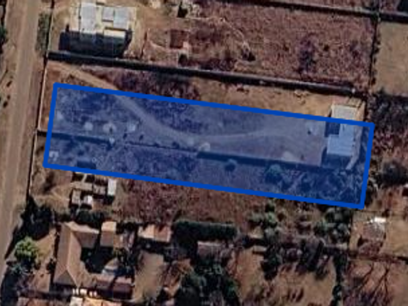 Aerial view of a rectangular residential plot featuring a boundary wall and internal driveway access.