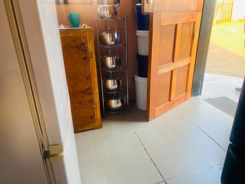 A functional scullery or utility area featuring tiled flooring and a wooden door leading to the exterior.