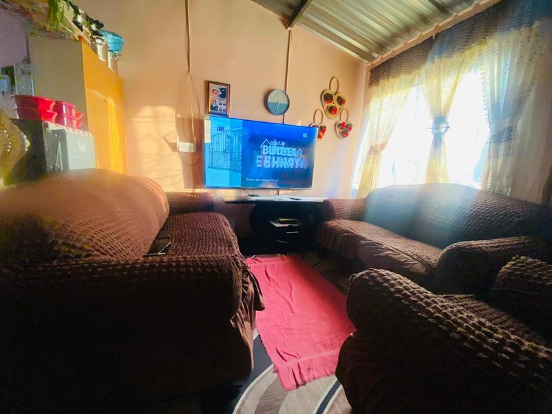 A living room space featuring a corrugated metal ceiling and natural light from the window.