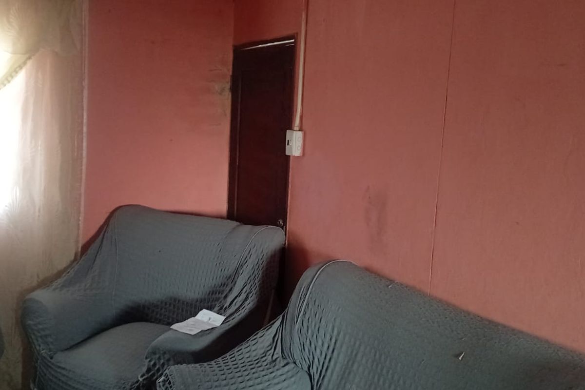 A living room area featuring plain walls and a timber door, currently requiring cosmetic updates to improve the overall aesthetic and condition.