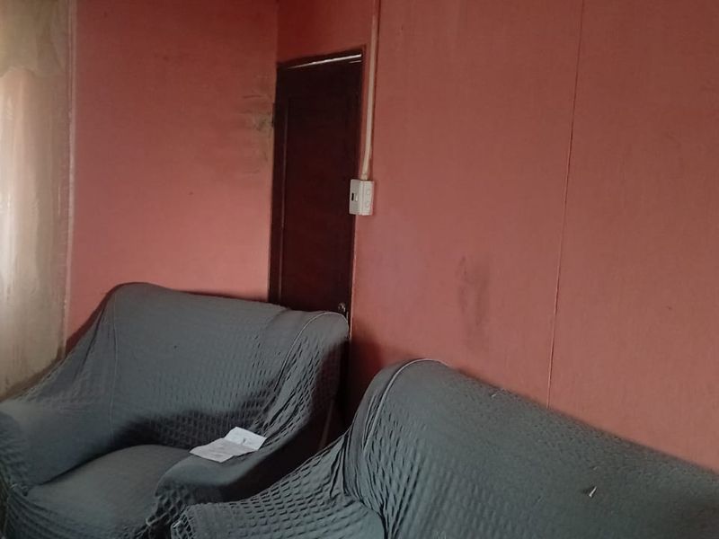 A living room area featuring plain walls and a timber door, currently requiring cosmetic updates to improve the overall aesthetic and condition.