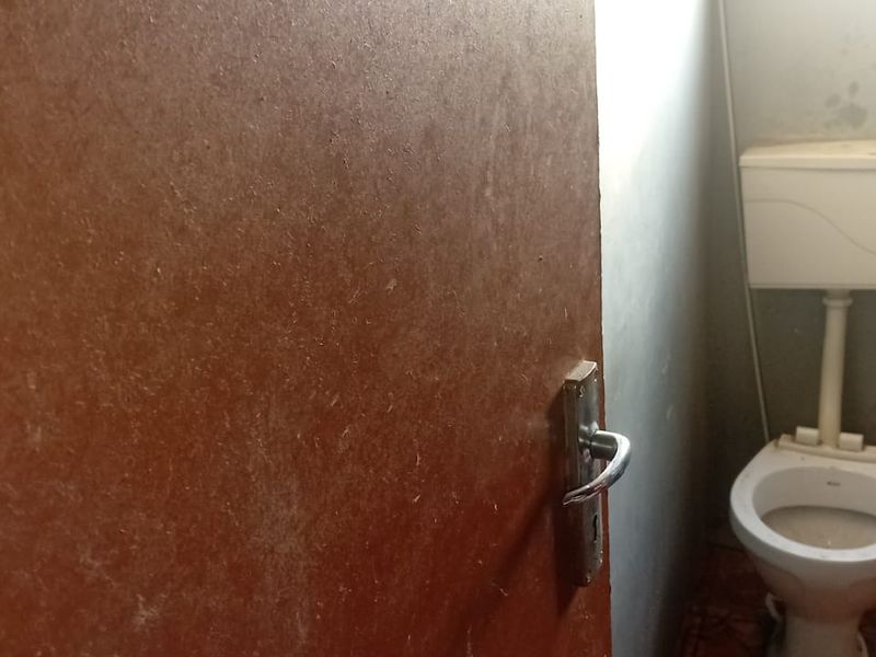 A small, basic bathroom featuring a standard toilet and cistern, currently showing signs of significant wear and requiring cosmetic updates.