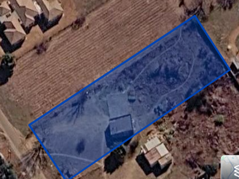 Aerial view of a vacant land plot with boundary lines highlighted, showing the property's position within the surrounding landscape.