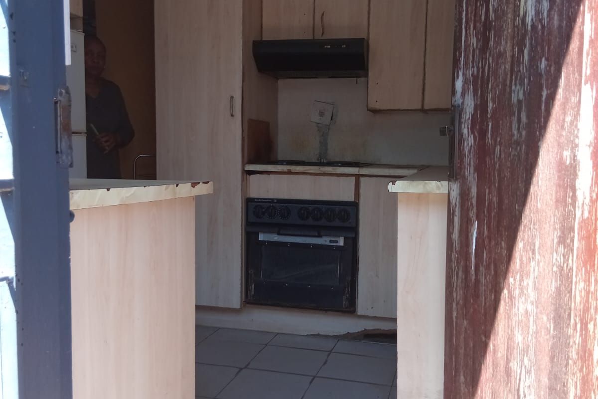 A compact kitchen featuring built-in cabinetry, an integrated oven and hob, and tiled flooring, requiring some cosmetic updates to improve its overall condition.