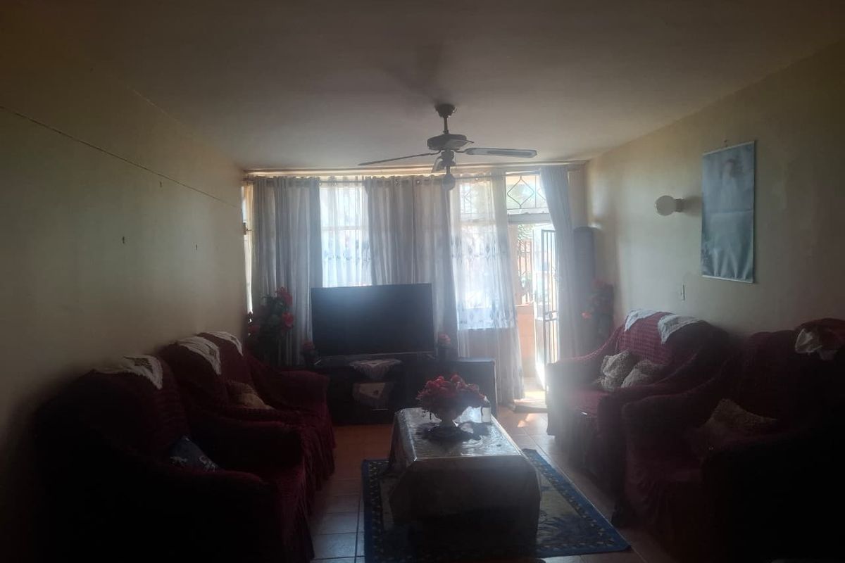 A living room featuring tiled flooring, a ceiling fan, and access to an outdoor area through a sliding glass door.