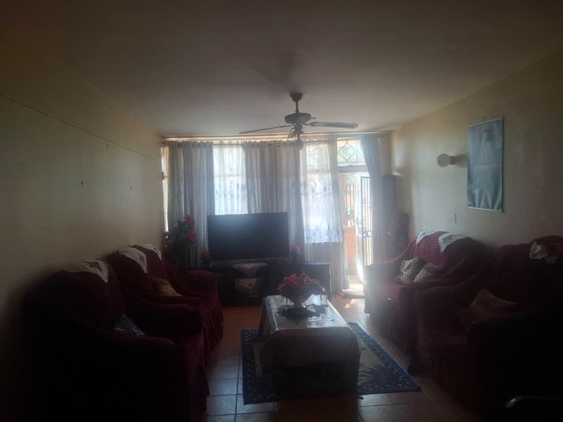 A living room featuring tiled flooring, a ceiling fan, and access to an outdoor area through a sliding glass door.