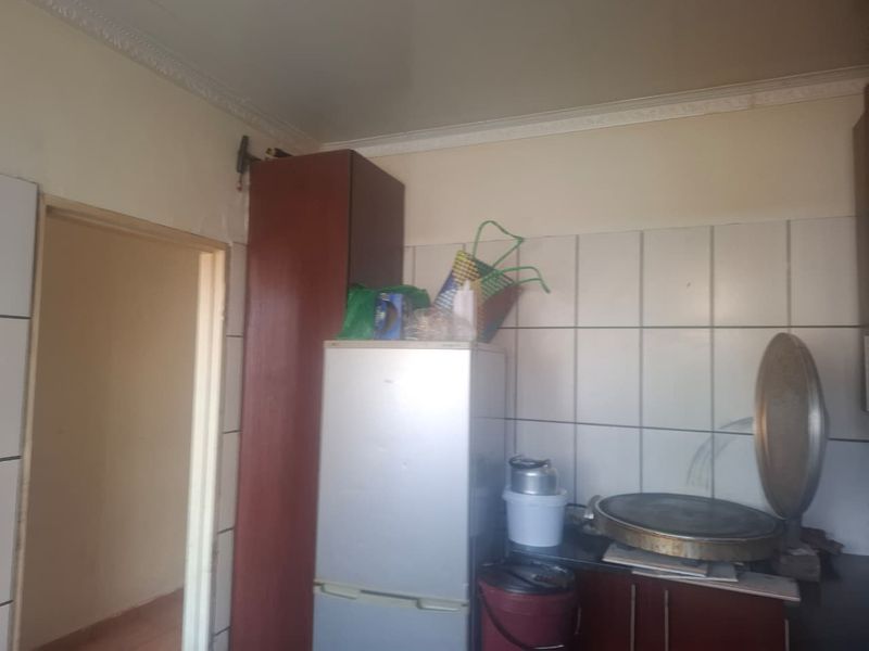 A compact kitchen area featuring tiled backsplashes and built-in cabinetry, requiring cosmetic updates to improve the overall aesthetic and finish.