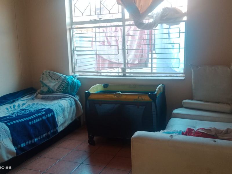 A bedroom featuring tiled flooring and a window fitted with security bars, providing natural light to the space.