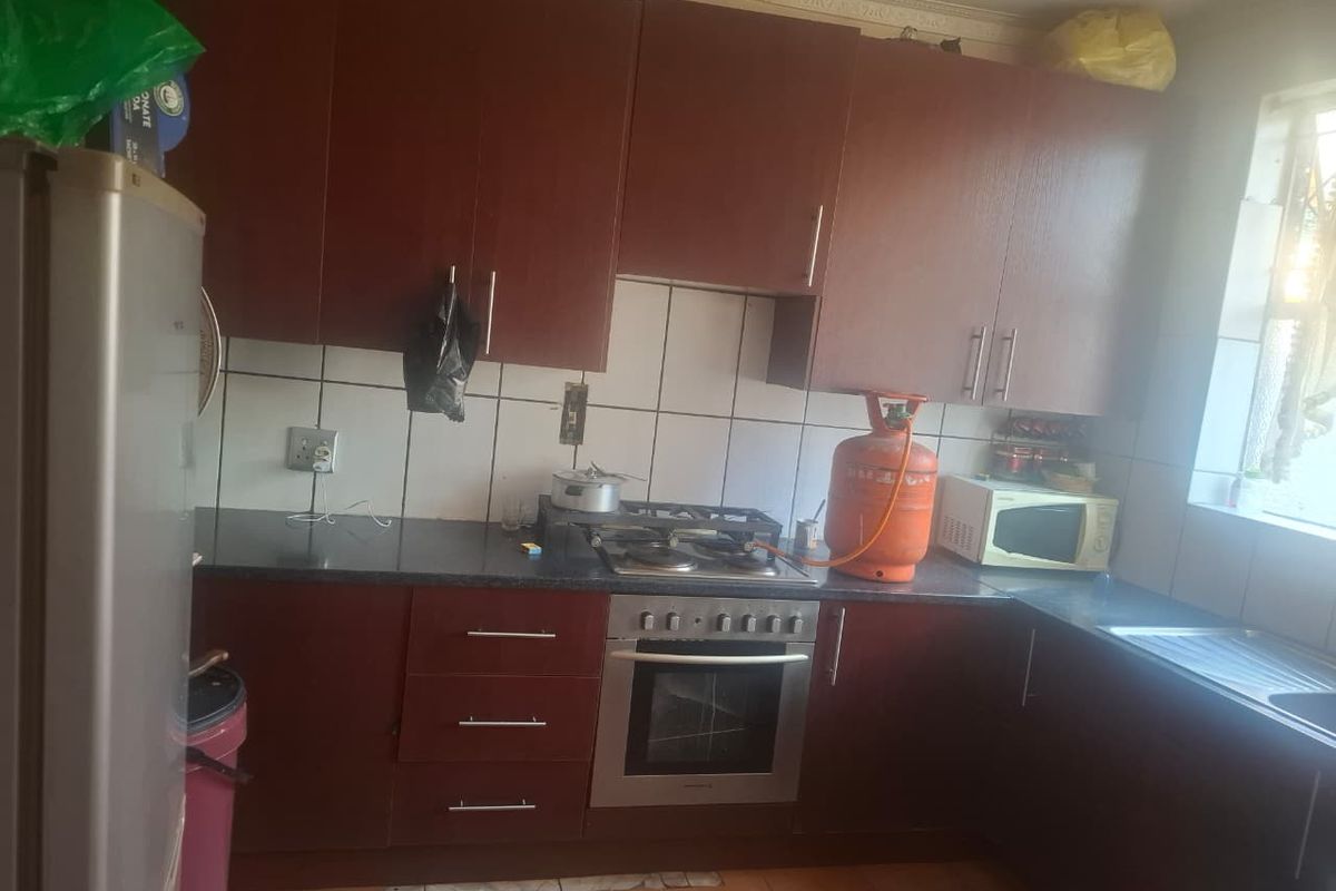 A functional kitchen featuring dark wood-look cabinetry, a built-in oven with gas hob, tiled backsplash, and tiled flooring, offering a practical layout for daily use.