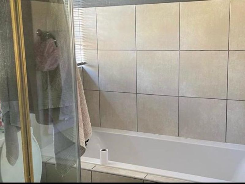 A functional bathroom featuring a bathtub, a separate shower enclosure, and a toilet with neutral wall tiling.
