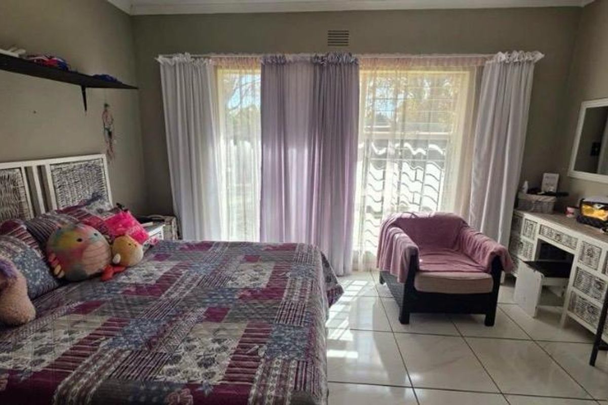 A bedroom featuring tiled flooring, a built-in vanity, and a sliding glass door providing natural light.