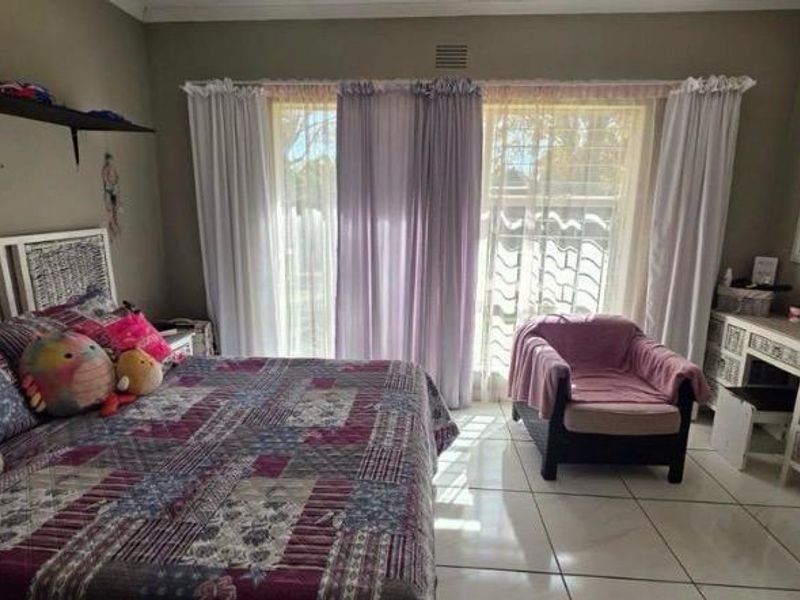 A bedroom featuring tiled flooring, a built-in vanity, and a sliding glass door providing natural light.
