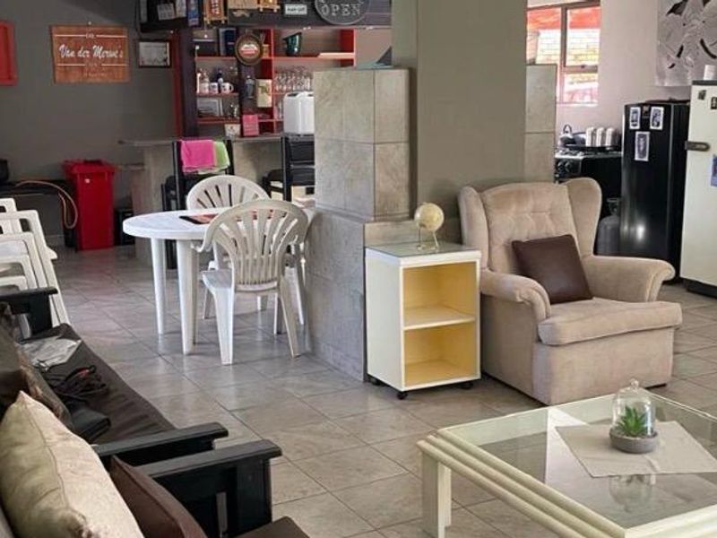 Spacious open-plan living area featuring tiled flooring, a central support pillar, and a built-in bar counter, offering versatile space for relaxation and entertaining.