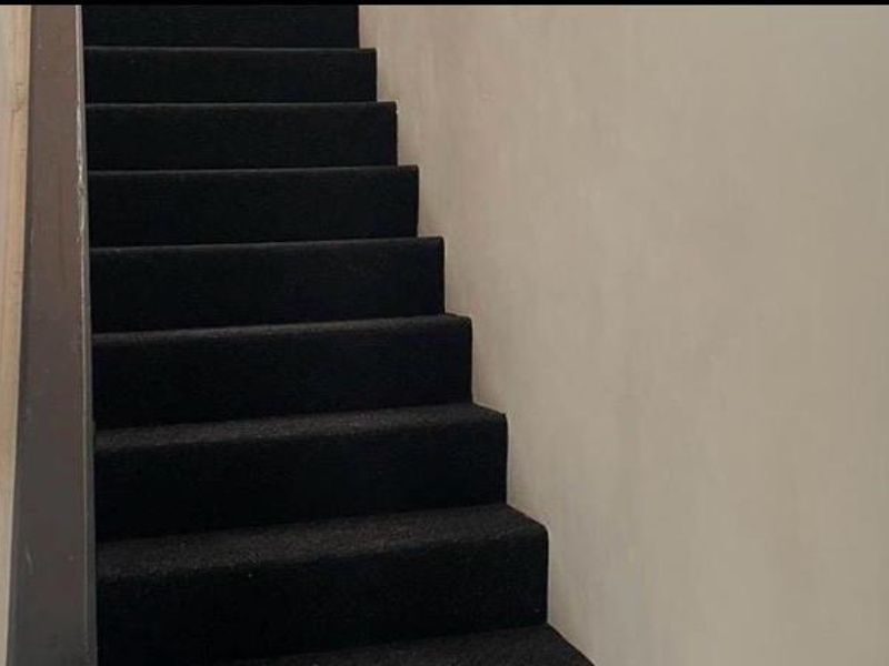 A simple staircase with dark carpeting and plain walls, providing access between levels.