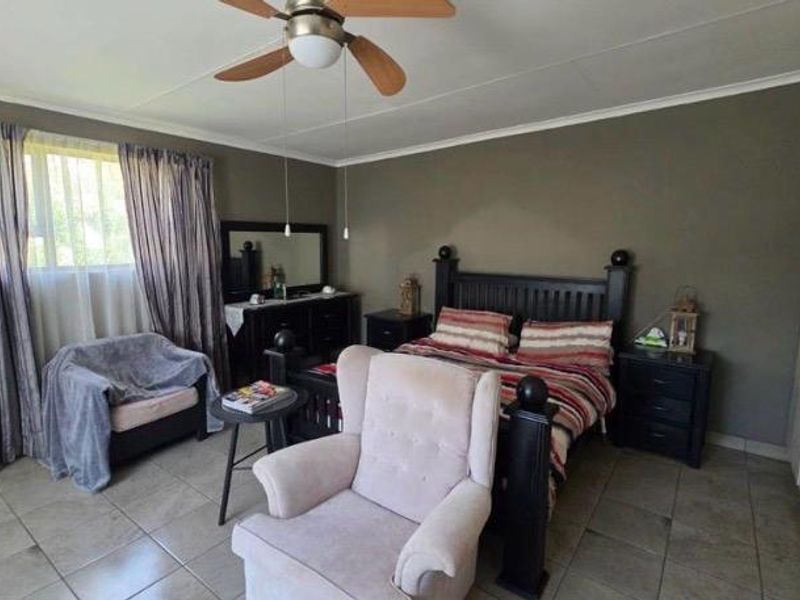 A bedroom featuring tiled flooring, a ceiling fan, and built-in cupboards, providing functional storage and basic amenities.