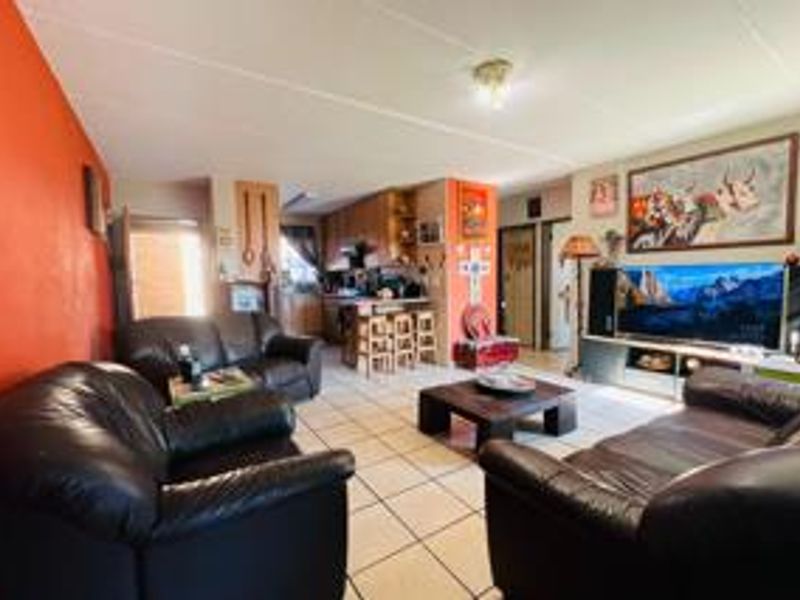 Open-plan living and kitchen area featuring ceramic tiled flooring and built-in kitchen cabinetry with a breakfast counter.